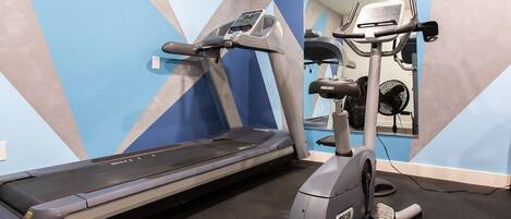 A gym with a treadmill, elliptical, and a mirrored wall.