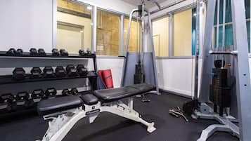 A gym with weightlifting equipment, dumbbells, and benches.