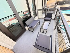Een balkon met een zithoek, bestaande uit een bank en twee stoelen, plus een bijzettafeltje.