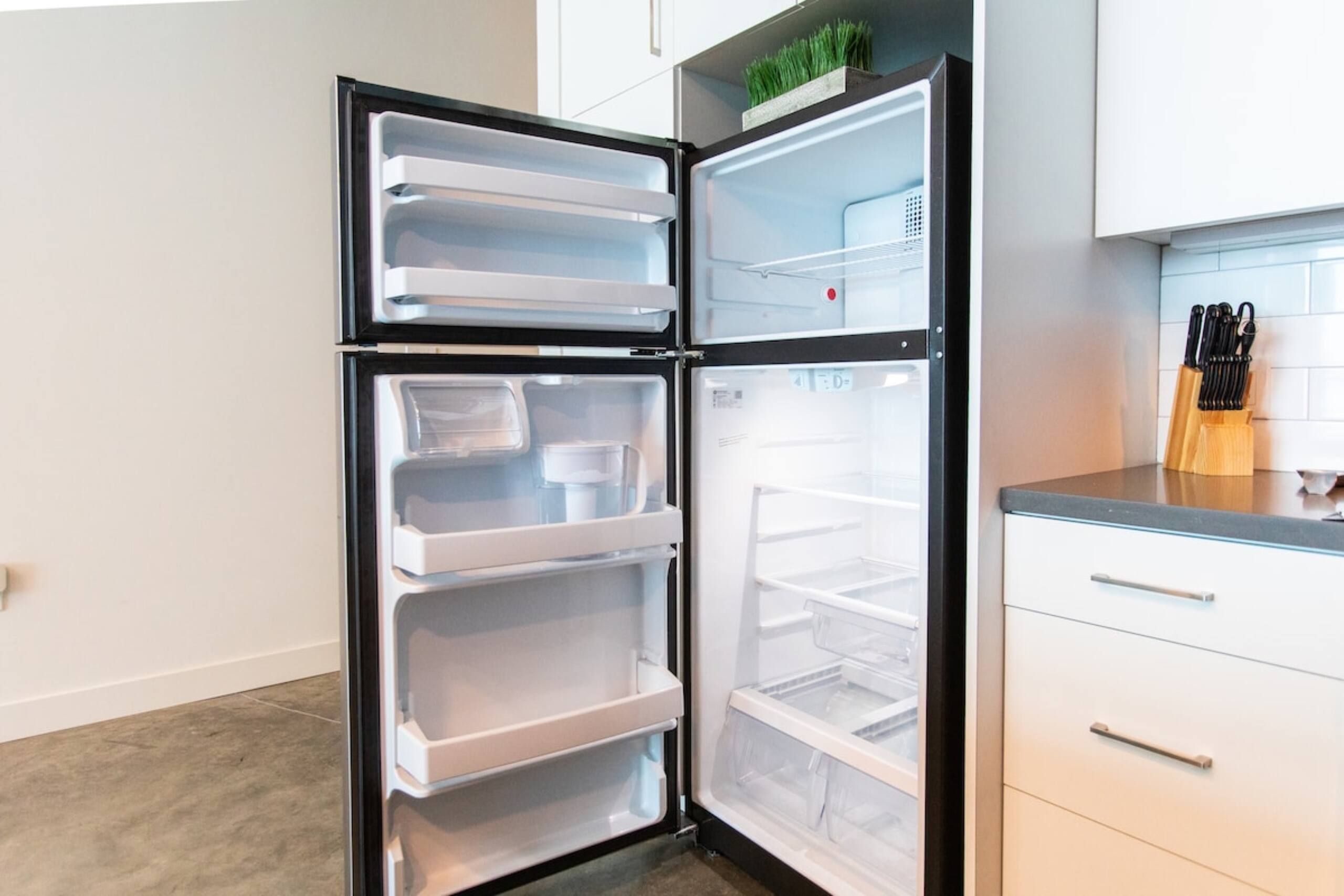 A modern kitchen with a built-in double-door refrigerator, white cabinetry, and a countertop with a knife block.