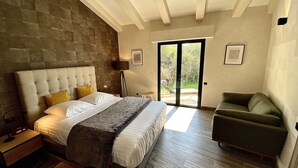 Un dormitorio con una cama grande, un sillón verde y vistas a través de un ventanal.