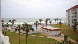 Un hôtel doté d’une piscine, offrant une vue sur la plage et bordé de palmiers.