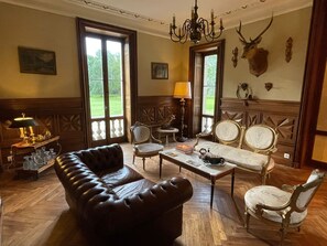 A traditional room with a leather sofa, a wooden coffee table, and a chandelier. - Fairytale castle with heated outdoor pool (Brain-sur-Allonnes)