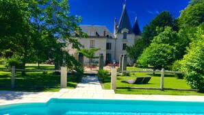 A swimming pool with a stone pathway leading to a building with a tower. - Fairytale castle with heated outdoor pool (Brain-sur-Allonnes)