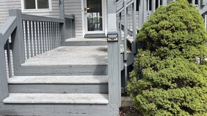 Una escalera de madera que lleva a una puerta con un pequeño panel solar en el poste.