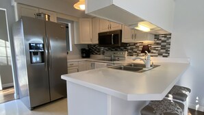 A modern kitchen with a stainless steel refrigerator, a built-in microwave, and a large island with bar stools. - Beautiful Lake View IYopawa Island Home. Backs up to Golf Course (Coldwater)
