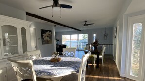 A spacious dining area with a large round table, white chairs, and a ceiling fan. - Beautiful Lake View IYopawa Island Home. Backs up to Golf Course (Coldwater)