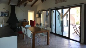 A spacious kitchen with a wooden table and chairs, a large window, and a sliding glass door leading to an outdoor area. - Single-storey villa, sea view, swimming pool, 5' from beaches, peaceful setting. (Coti-Chiavari)