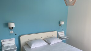 A neatly made bed with white linens, a bedside table with a lamp, and a wall-mounted charging station. - Single-storey villa, sea view, swimming pool, 5' from beaches, peaceful setting. (Coti-Chiavari)