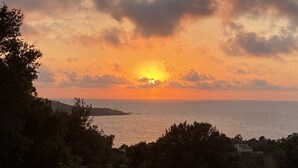 A sunset over a coastal landscape with trees and a distant shoreline. - Single-storey villa, sea view, swimming pool, 5' from beaches, peaceful setting. (Coti-Chiavari)