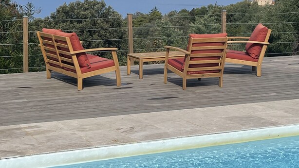 A poolside area with wooden chairs and a table, overlooking a clear blue sea and distant islands. - Single-storey villa, sea view, swimming pool, 5' from beaches, peaceful setting. (Coti-Chiavari)