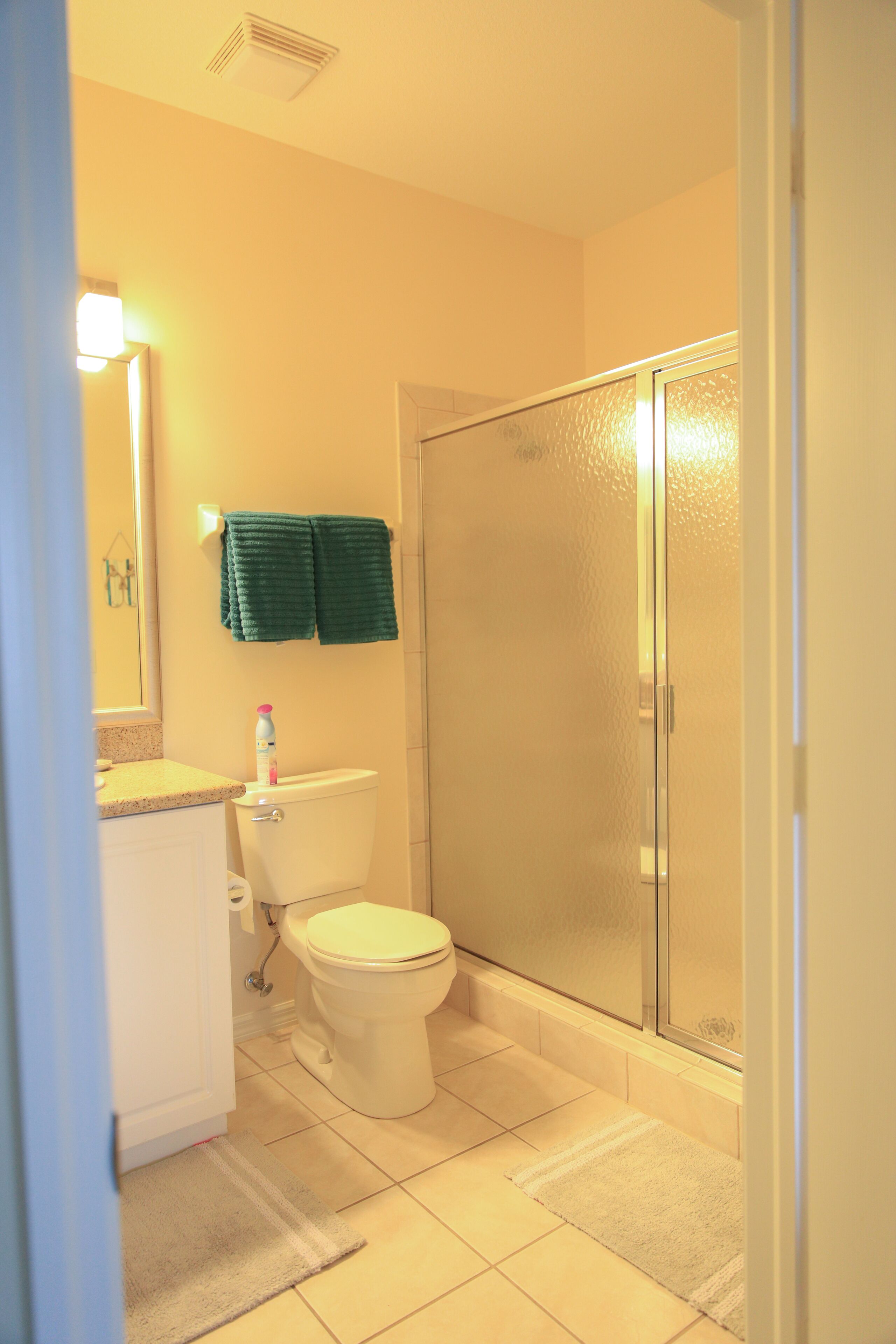 Une salle de bain comprenant des toilettes, un lavabo, un miroir et une douche avec une porte en verre.