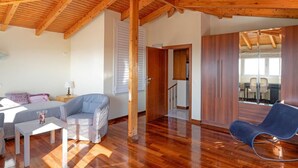 A spacious living area with wooden flooring, a sofa, a chair, and a small table. - Villa with pool and magnificent ocean views half mile from sandy beach (Saronida)