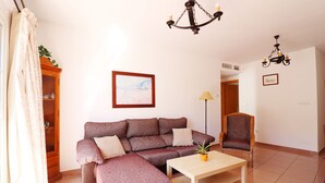 Uma sala de estar com sofá, poltrona, mesa e lustre.