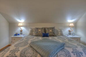 A bedroom with a large bed, two bedside tables with lamps, patterned bedding, and a blue throw blanket. - Bramble Seaview Cottage (Entire Property) with Sparkly Water View in Eastsound (Eastsound)