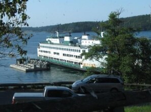 A riverboat docked at a pier with a view of a forested shoreline. - Bramble Seaview Cottage (Entire Property) with Sparkly Water View in Eastsound (Eastsound)