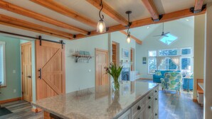 Una cocina amplia con una isla grande, vigas de madera e iluminación colgante.