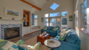 Una sala de estar acogedora con chimenea, sofás azules, una mesa de centro y un tragaluz.