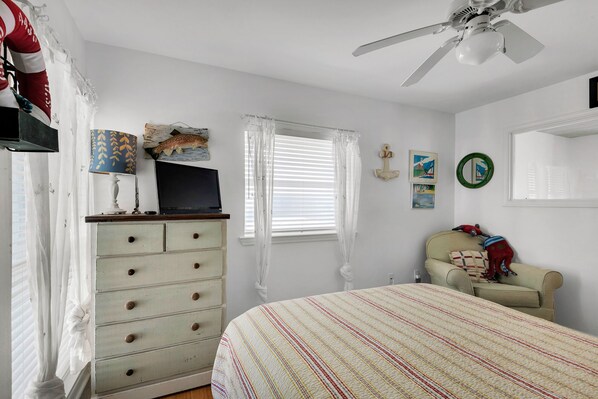A bedroom with a bed, dresser, television, and decorative items. - Gulf front, pet friendly, and breath-taking views! (Pensacola Beach)