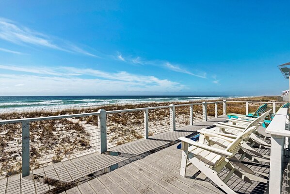 A beachside deck with a view of the ocean, a wooden walkway, and beach chairs. - Gulf front, pet friendly, and breath-taking views! (Pensacola Beach)