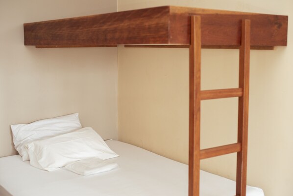 A bunk bed with a wooden ladder and white bedding.