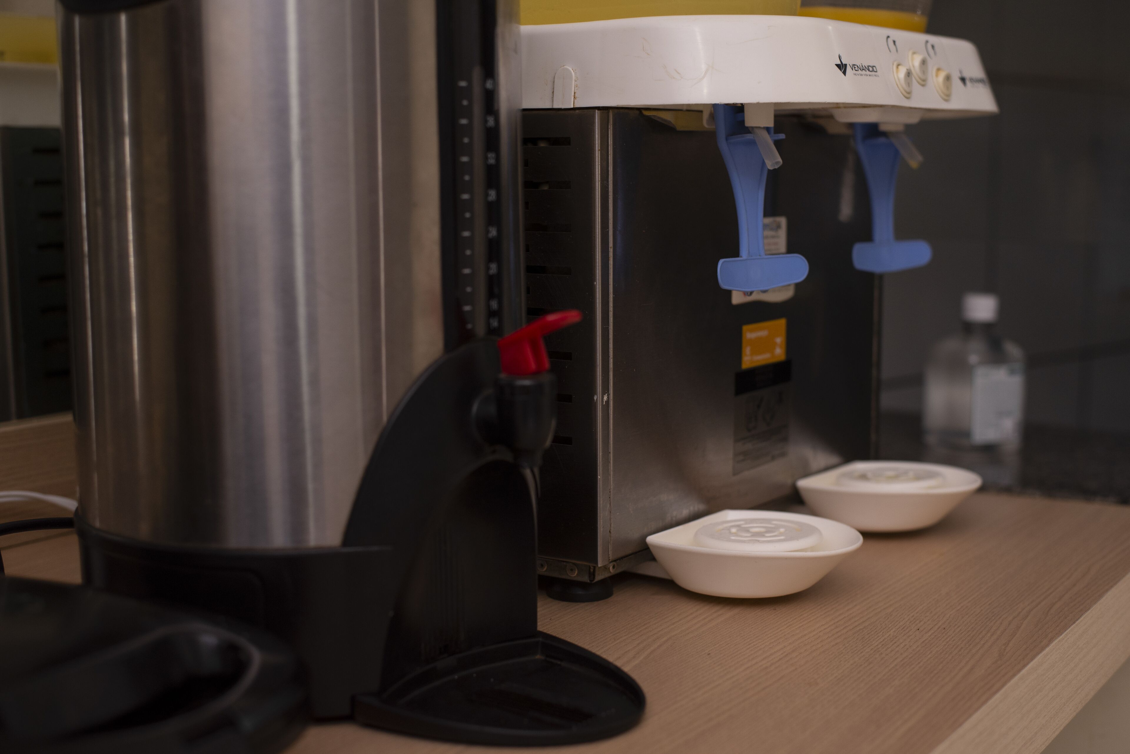 Una máquina de café con dos tazas blancas y un recipiente de acero inoxidable.