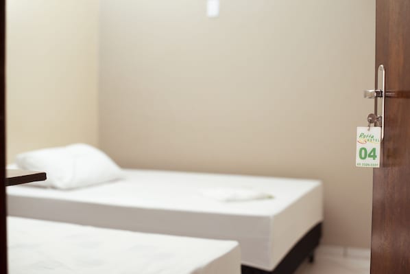 Habitación de hotel con dos camas individuales, una puerta de madera y un cartel con el número de habitación.