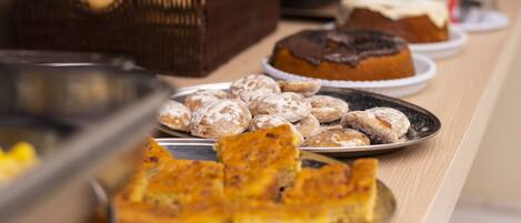 A buffet table with various baked goods including pastries and cakes.