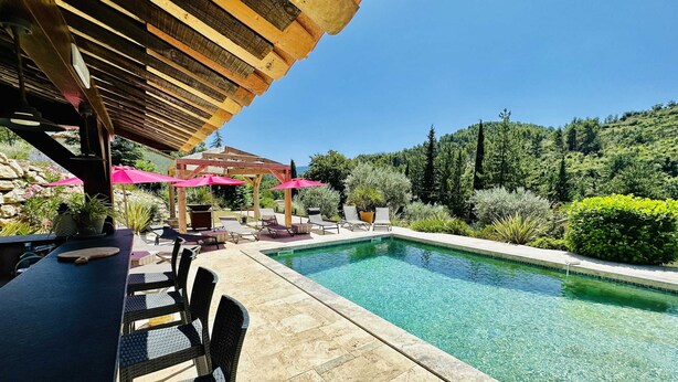 Zona de piscina con pérgola, sillones de descanso y una mesa con una pala.