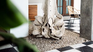 Un interior moderno con una gran escultura abstracta, suelo a cuadros y una silla de madera.