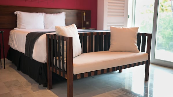 A modern bedroom with a bed, a wooden bench with cushions, and a large window.