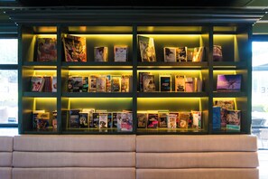 A bookshelf with books, a bench, and a window.