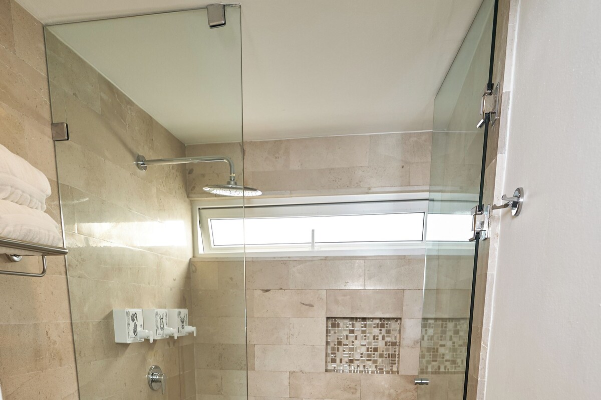 Un baño con ducha de vidrio, un inodoro y piso de baldosas.