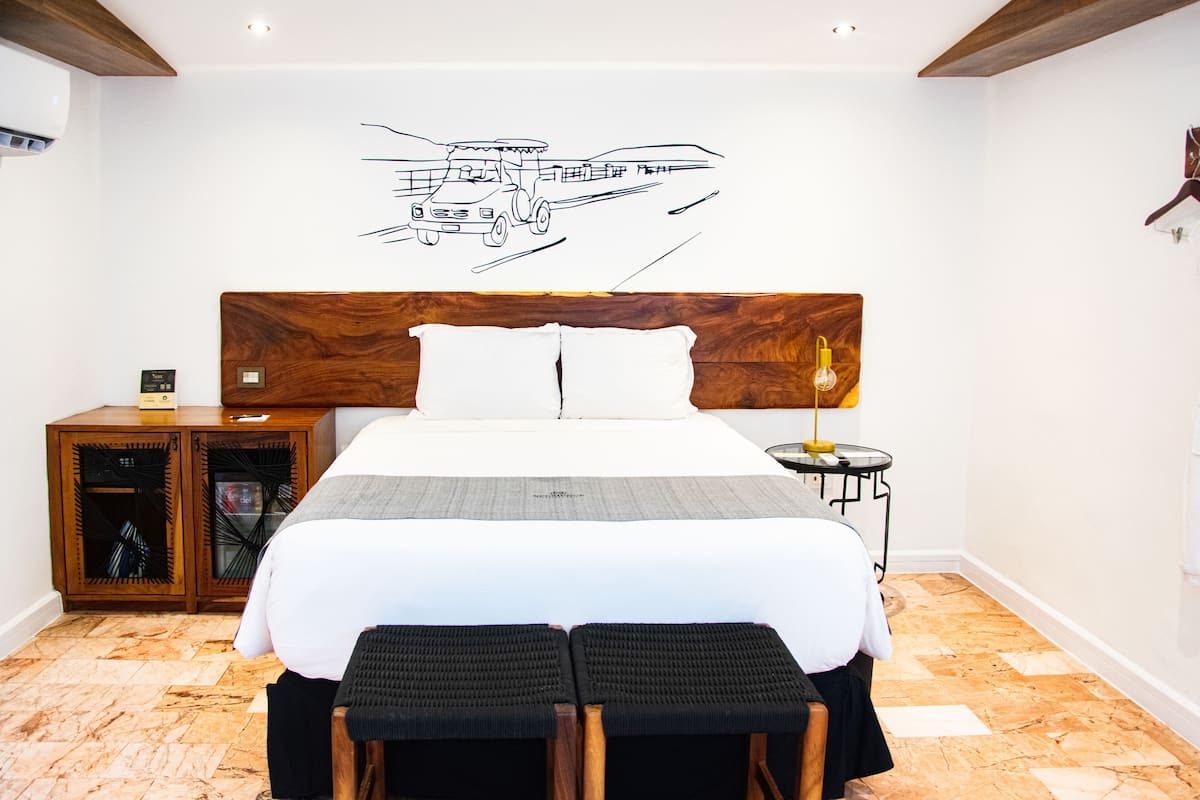 Un dormitorio ordenado con una cama grande, cabecera, mesitas de noche y una obra de arte en la pared con la imagen de un camión.