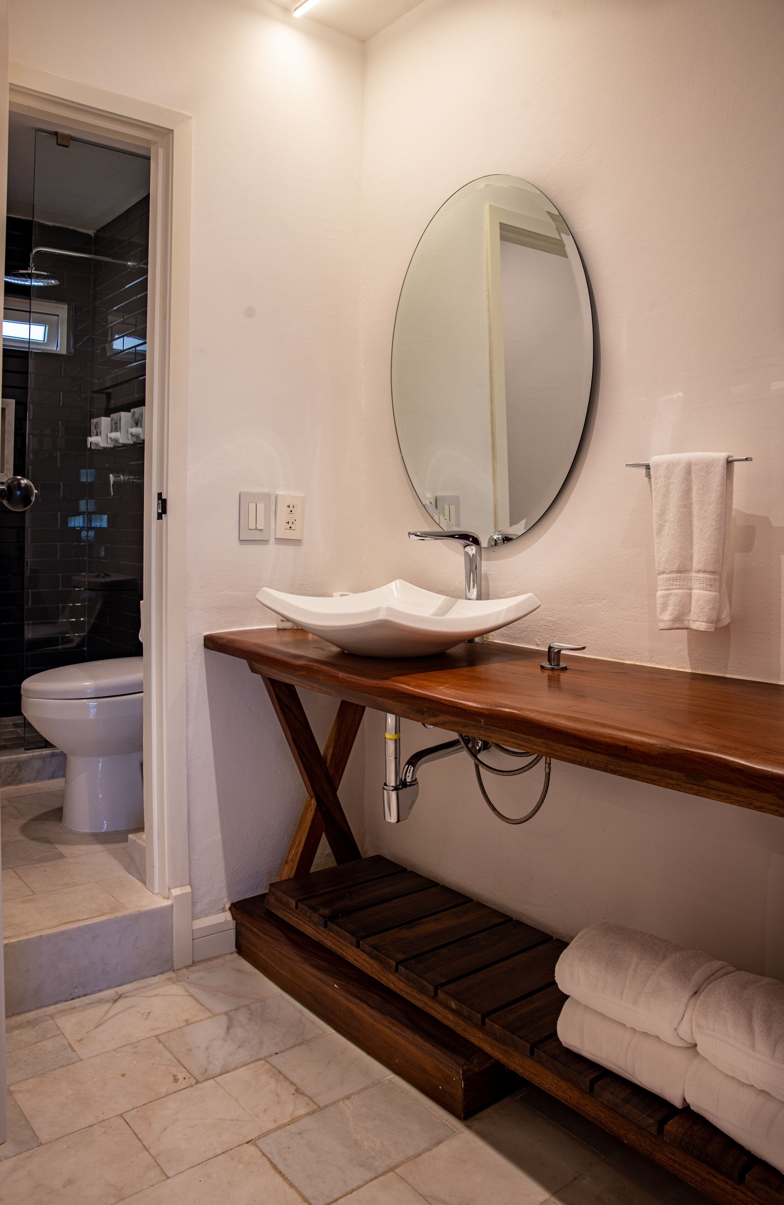 A bathroom with a white sink, a round mirror, and a towel rack.