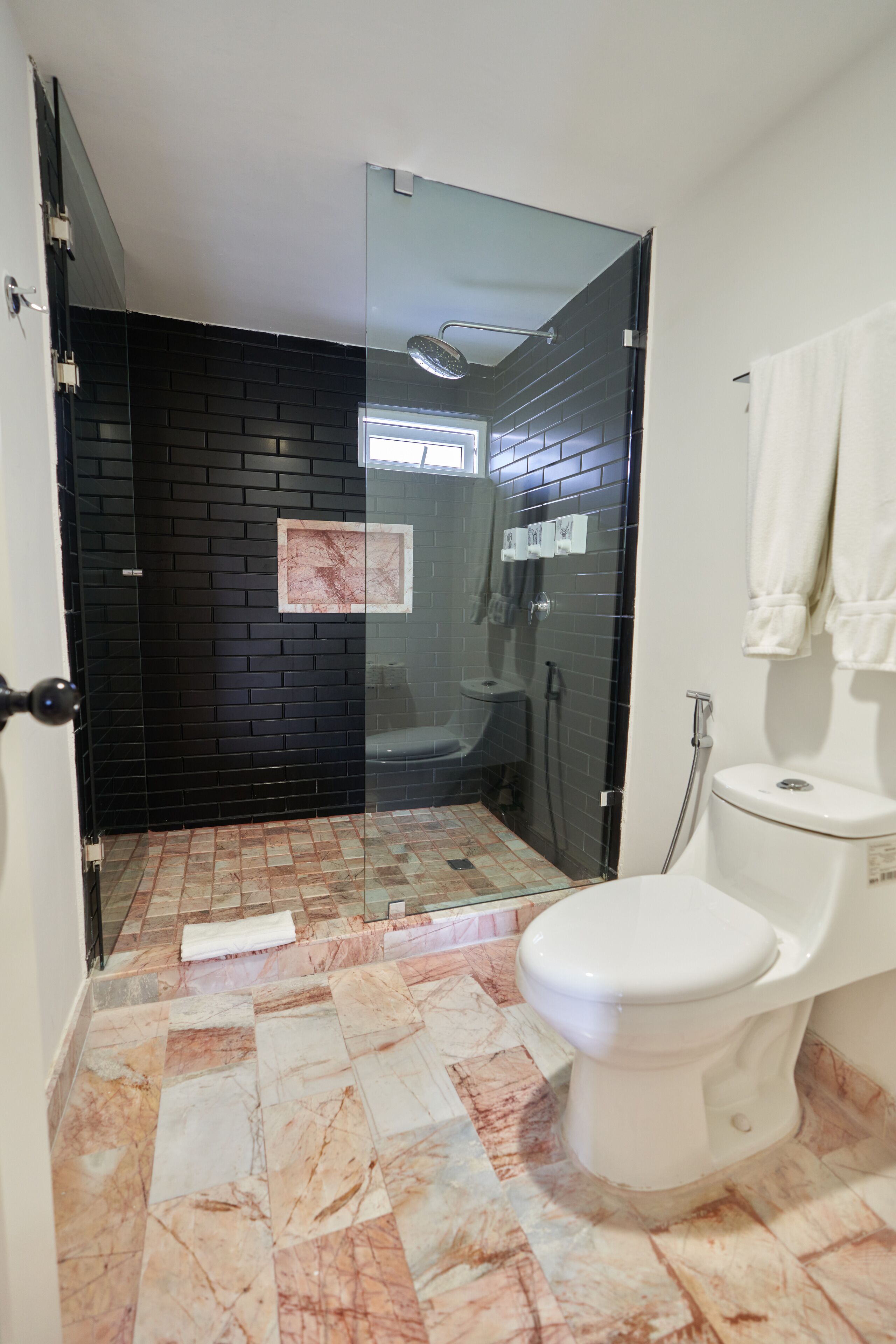 A bathroom with a glass-enclosed shower, a toilet, and a tiled floor.