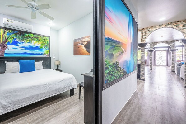 A hotel room with a bed, a desk, and a large painting of a landscape.
