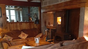 A cozy living room with a fireplace, wooden beams, and a sofa set.