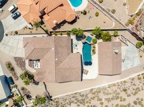 Vista aérea de uma propriedade residencial com vários edifícios, piscina e jardim bem cuidado.