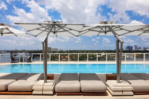 A rooftop pool area with lounge chairs and umbrellas, overlooking a city skyline. - Kimpton Shorebreak Fort Lauderdale Beach Resort by IHG (Fort Lauderdale)