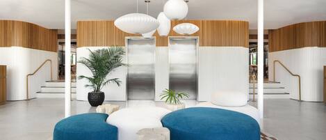 A modern lobby with a central seating area, a staircase, and a plant.