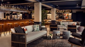 Un área de estar moderna con un bar, asientos y una planta decorativa.