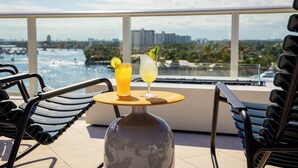 Un balcón con dos sillas, una mesa y dos bebidas.