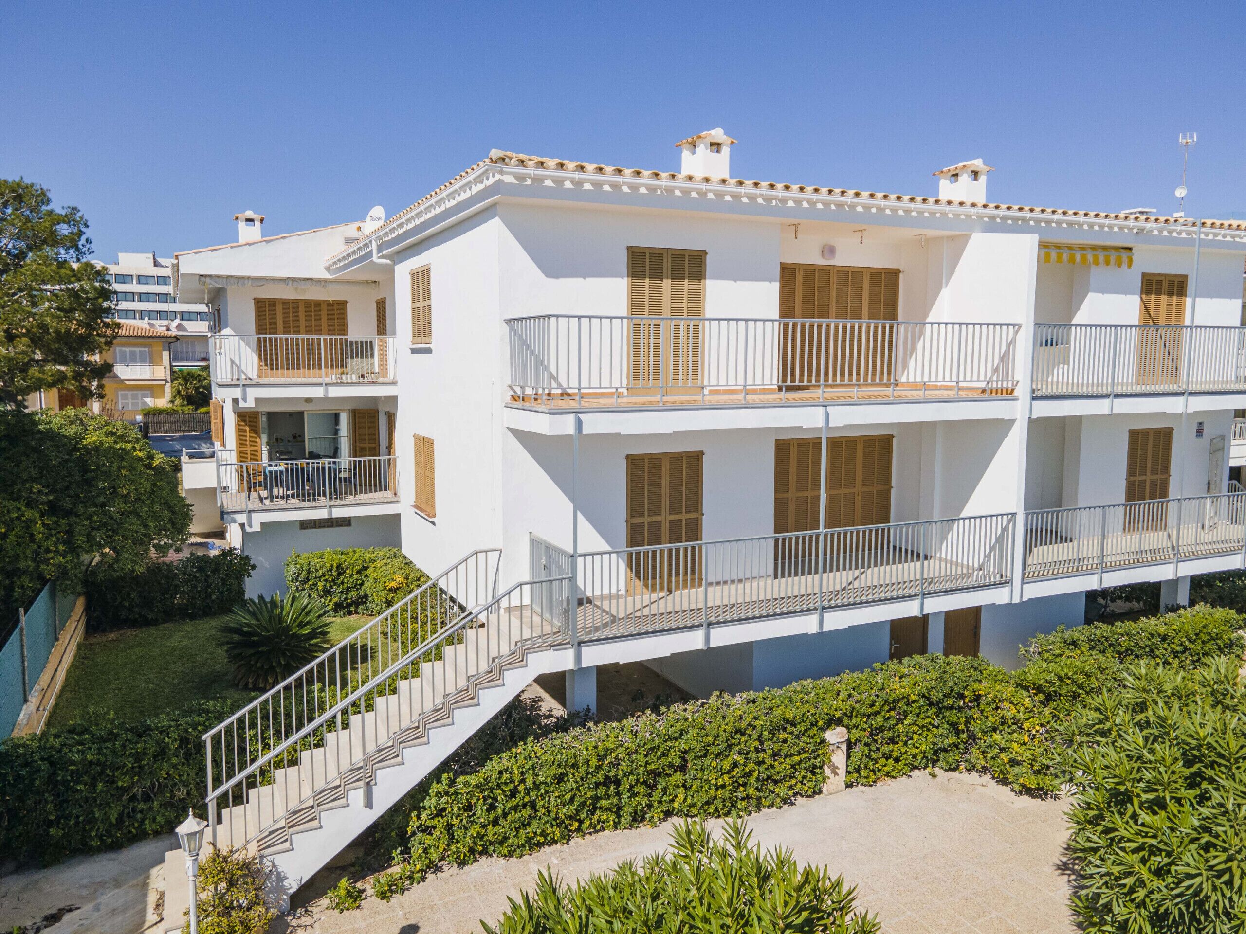 A multi-story building with balconies, a staircase, and a garden area.