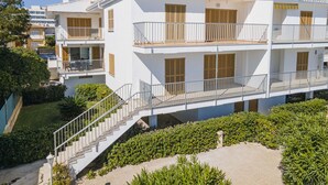A multi-story building with balconies, a staircase, and a garden area.