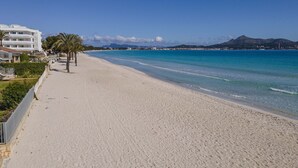A beach with a clear view of the ocean, a sandy shoreline, and a building with multiple floors on the left.