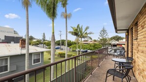 A balcony with a view of a street, palm trees, and a building labeled "Beach Street Family Practice". - Beach Street Bliss - situated in the heart of Woolgoolga (Woolgoolga)