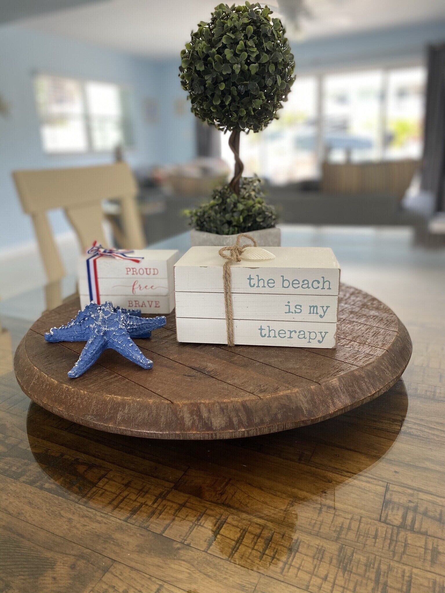 A wooden tray with a small potted plant, a starfish, and a wooden sign with text.