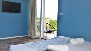 Ein Schlafzimmer mit Bett, Fernseher, Sessel und Blick ins Freie.