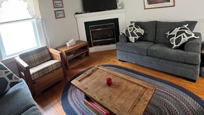 Een woonkamer met een open haard, een bank, een salontafel en een televisie.
